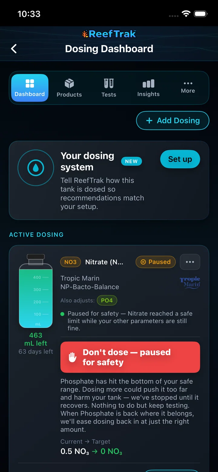 Reef Trak Dosing Dashboard on iPhone showing Add Dosing, dosing-system setup, an active product, bottle estimate, and a paused-for-safety warning